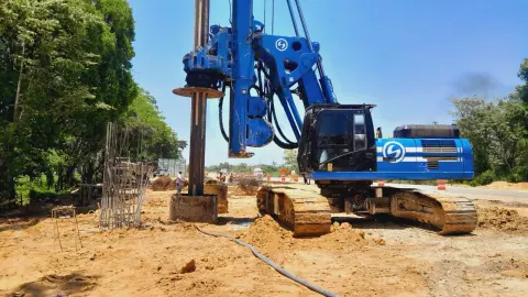 Perforadora hidráulica azul operando junto a armaduras de acero en una obra.
