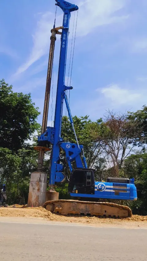 Perforadora hidráulica azul con el mástil elevado durante trabajos de cimentación.
